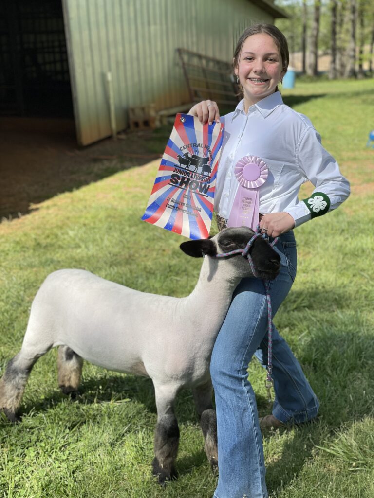 A girl poses with a sheep and a flyer.